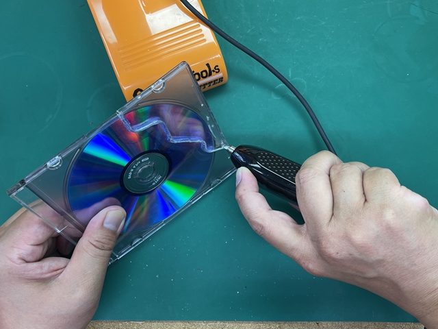 DVDケースとDVDを超音波カッターで切断中